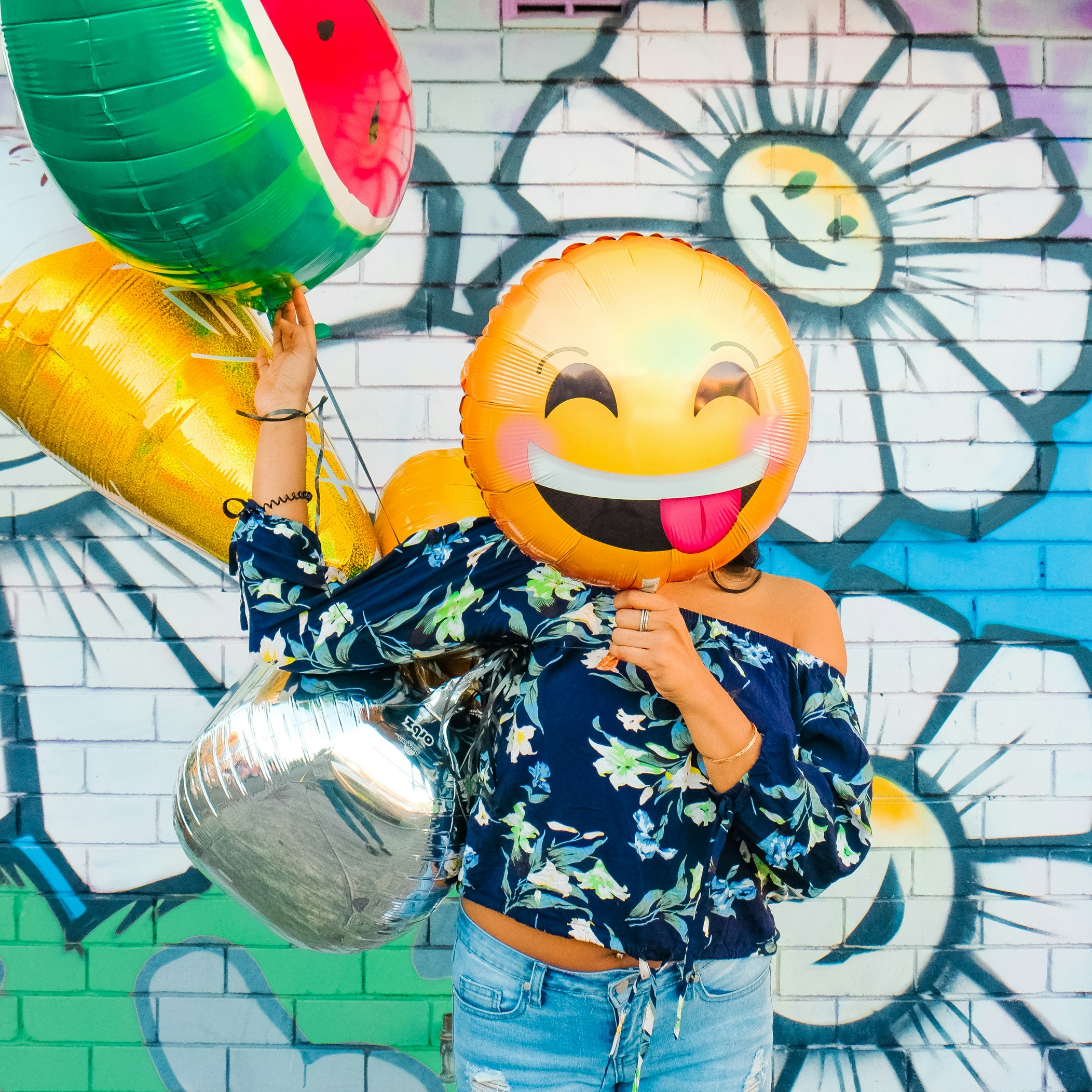 Besucherin mit einem lachenden Luftballon vor einer bunten Graffiti-Wand